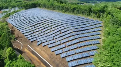 solar farm situated on a hillside, featuring rows of solar panels strategically positioned to capture sunlight. the area is bordered by dense green vegetation